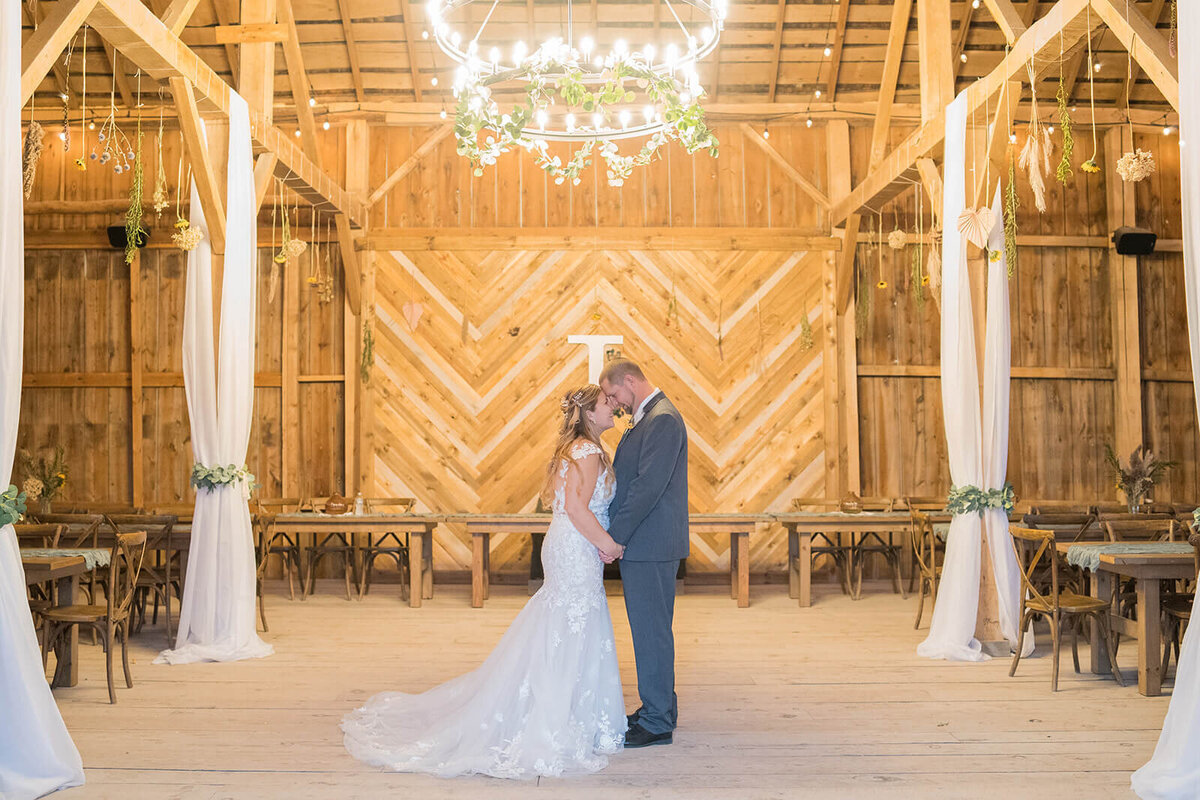 man and woman holding each other in a barn venue after their wedding