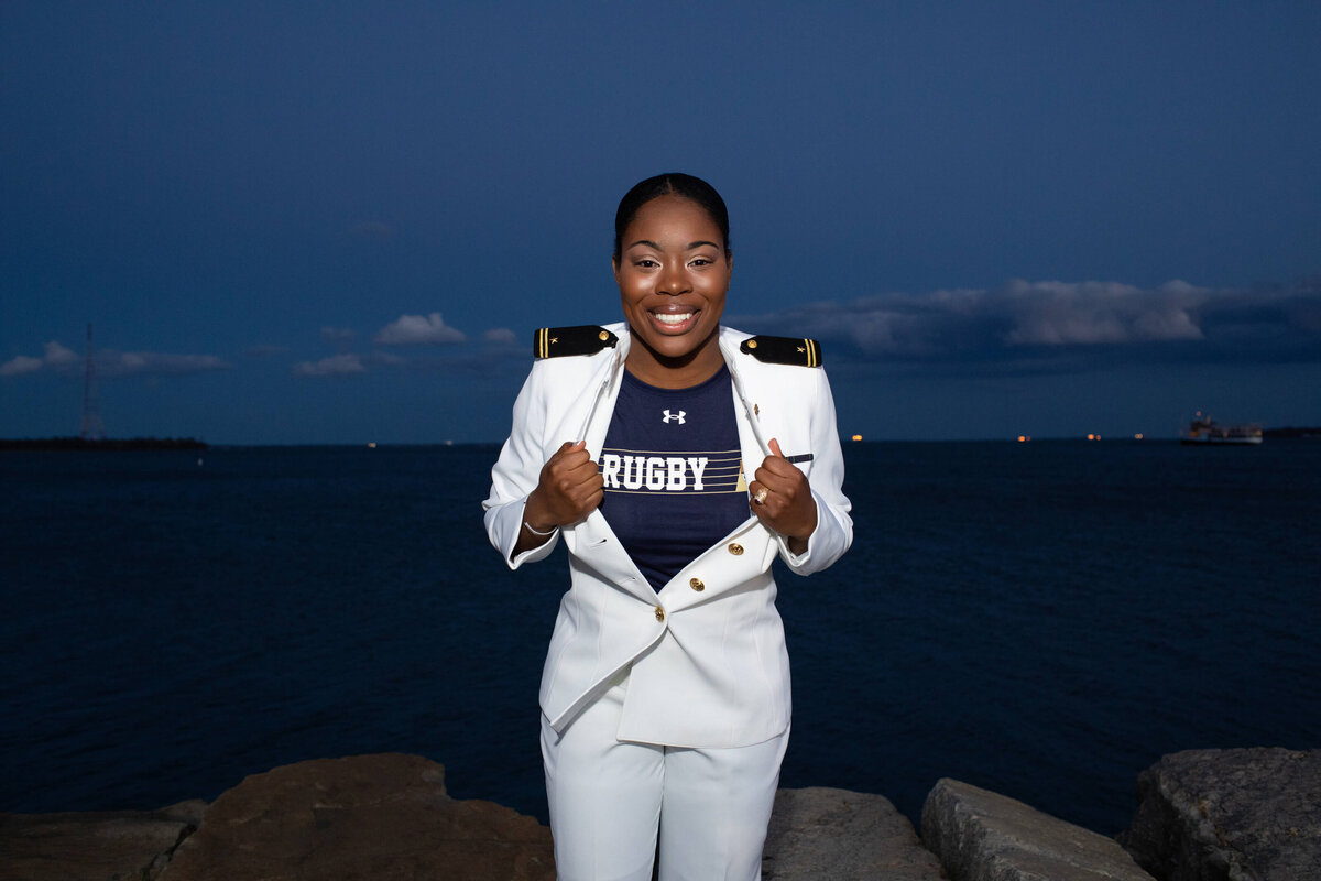 Navy Officer at Naval Academy shows women's rugby shirt in senior portrait.