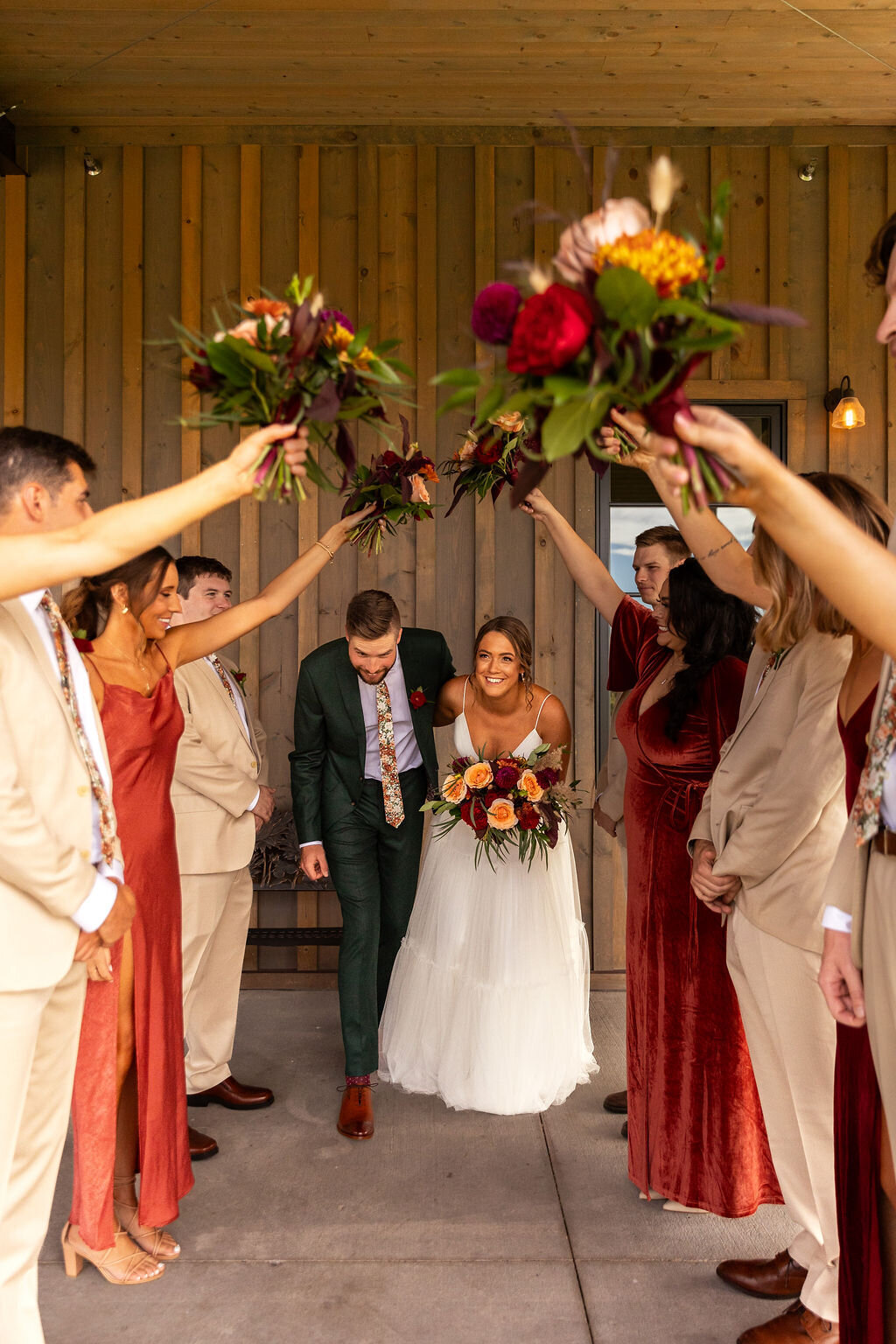 Bride and groom pose with their bridal party in fall colors.