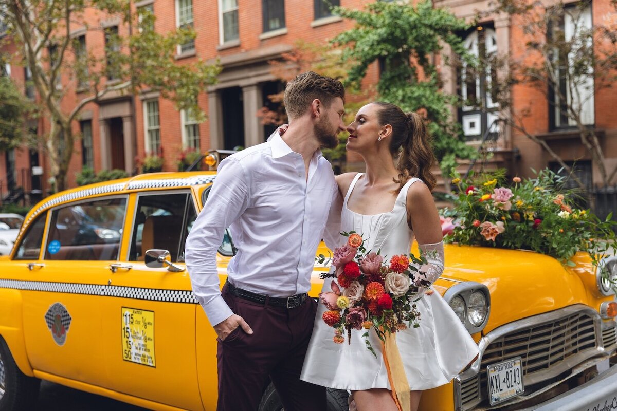 Bride and groom kissing in front of yellow NYC taxi