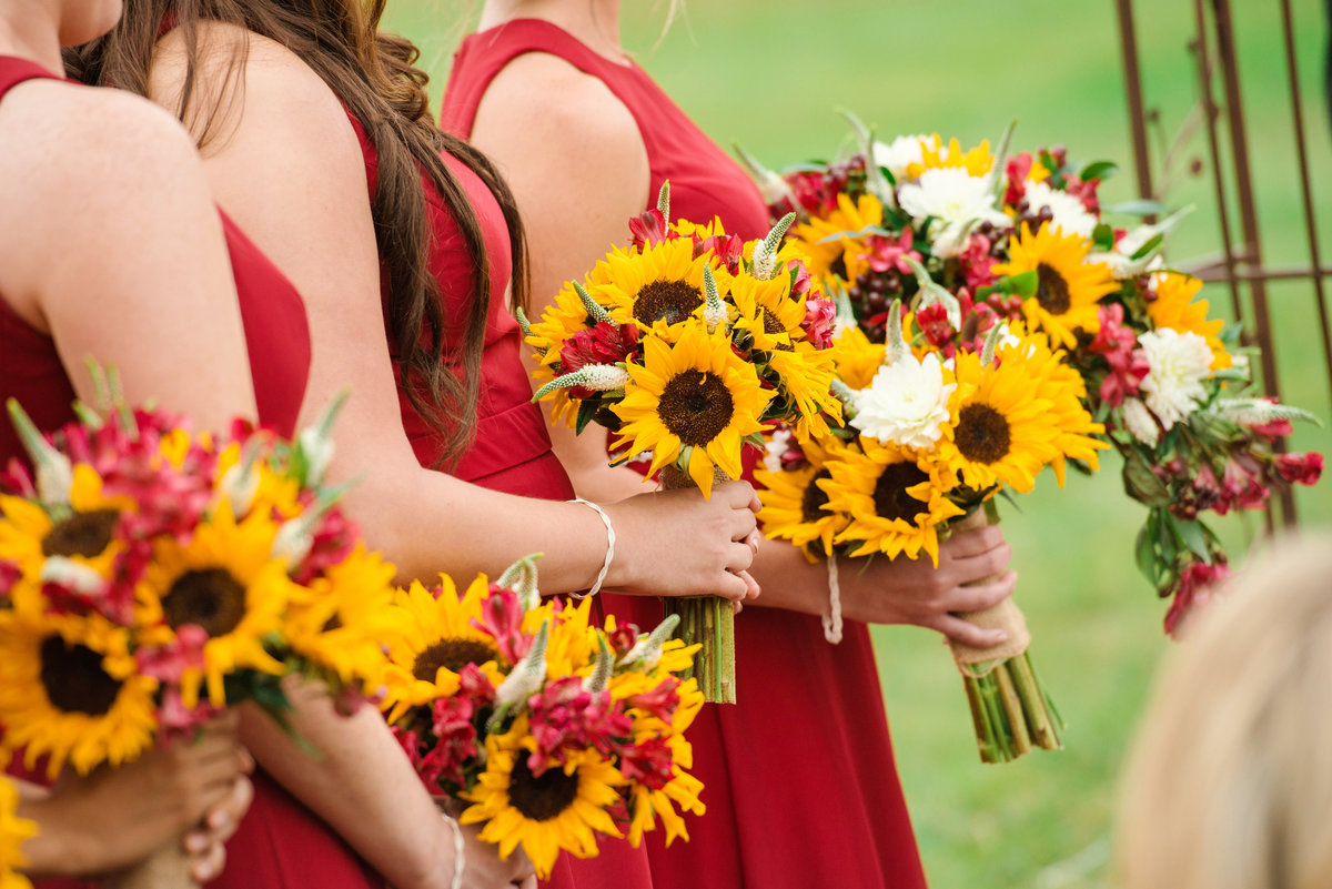 Bridesmaids holding sunflower bouquets during a wedding ceremony at The Bourne Mansion