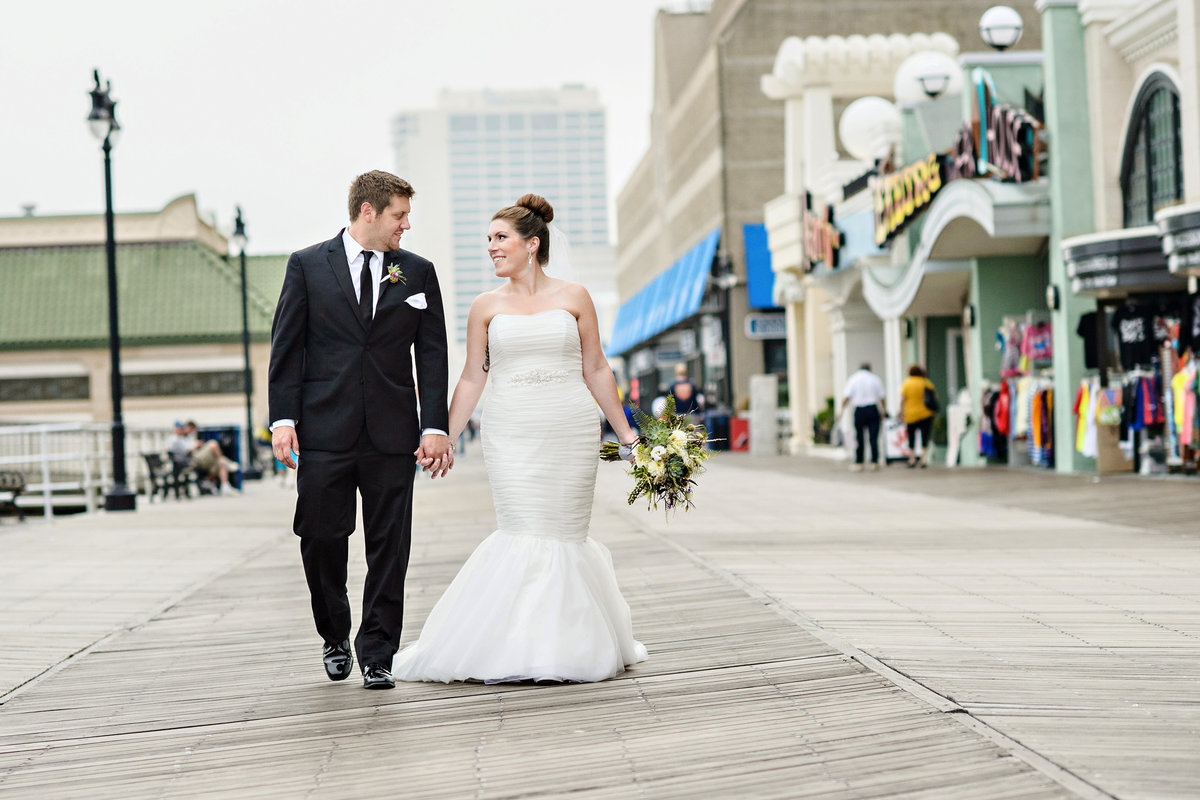 A bride and groom walk along the boardwalk outside their Chelsea Hotel Wedding.