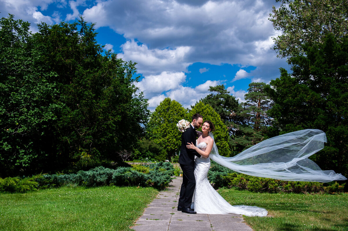 Ottawa wedding photography of a bride and groom  at the Ornamental Gardens.  The couple is hugging and the bride's veil is blowing in the wind.