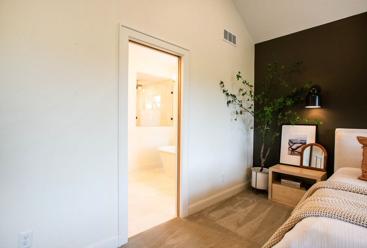 Spacious primary bedroom in custom Otsego home with natural light, wood floors and raised ceiling