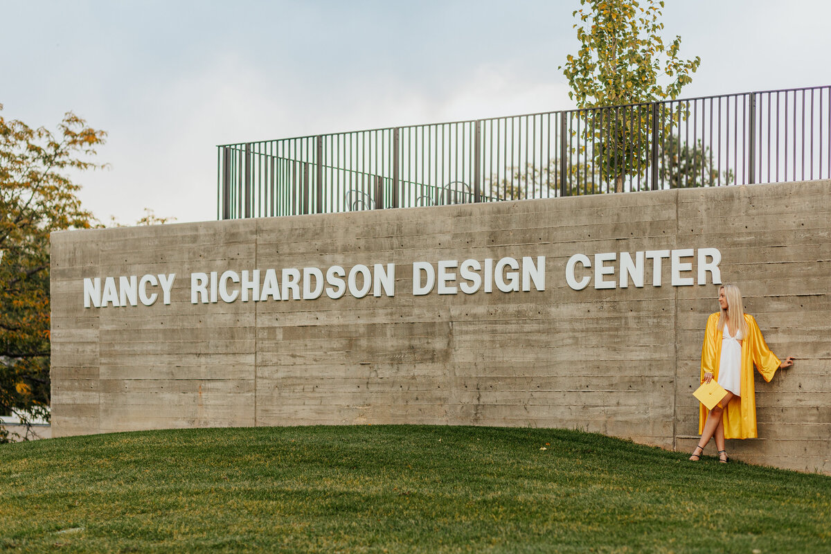 A Colorado State University graduate strikes a pose outside the Nancy Richardson Design Center in Fort Collins, Colorado.