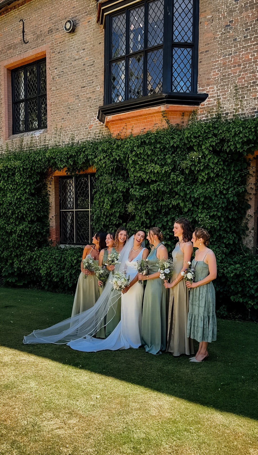 Bride and bridesmaids posing for photos and laughing after ceremony captured by Suffolk Wedding Content Creator