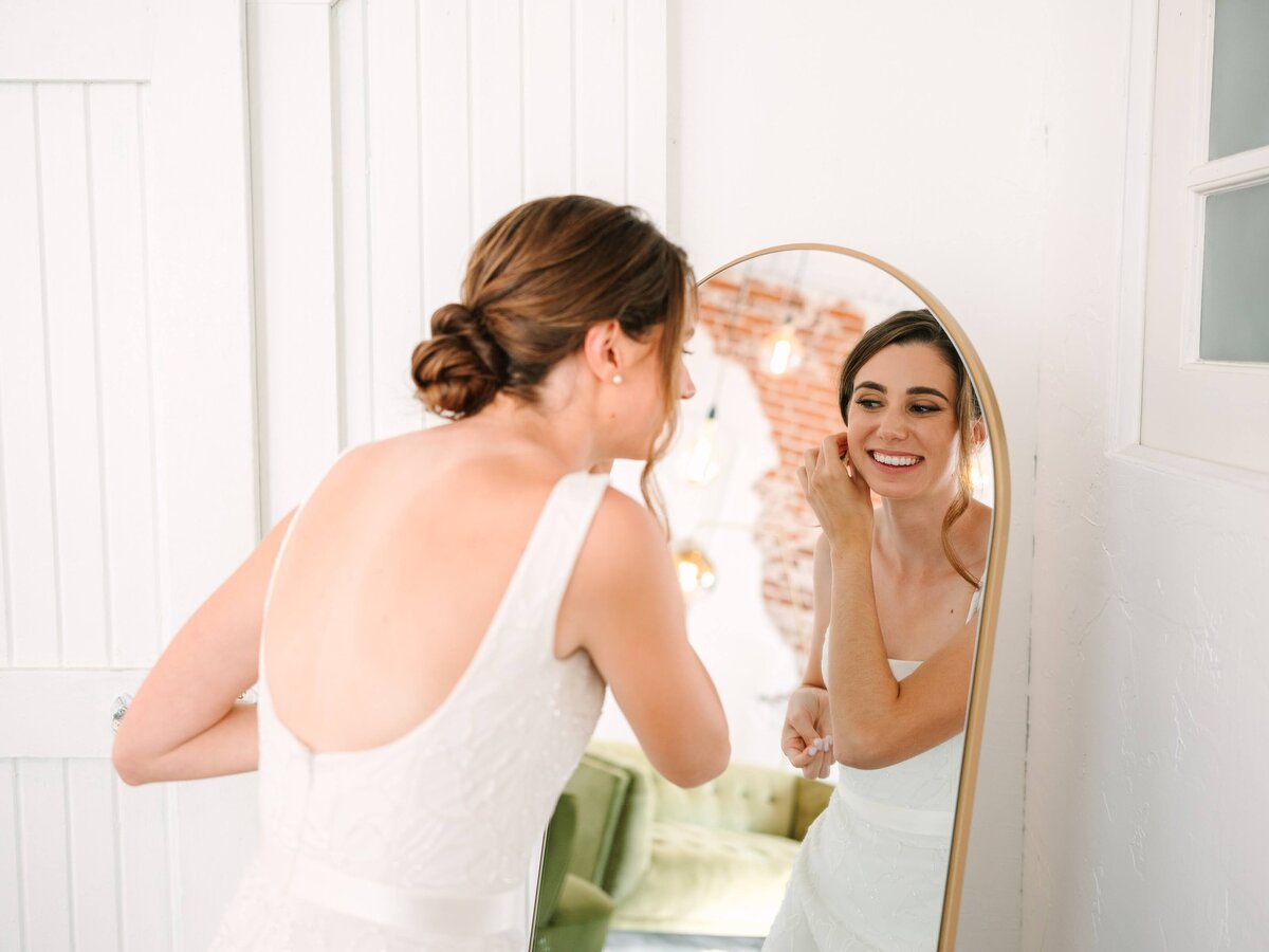 Bride puts on her earrings on her wedding day.