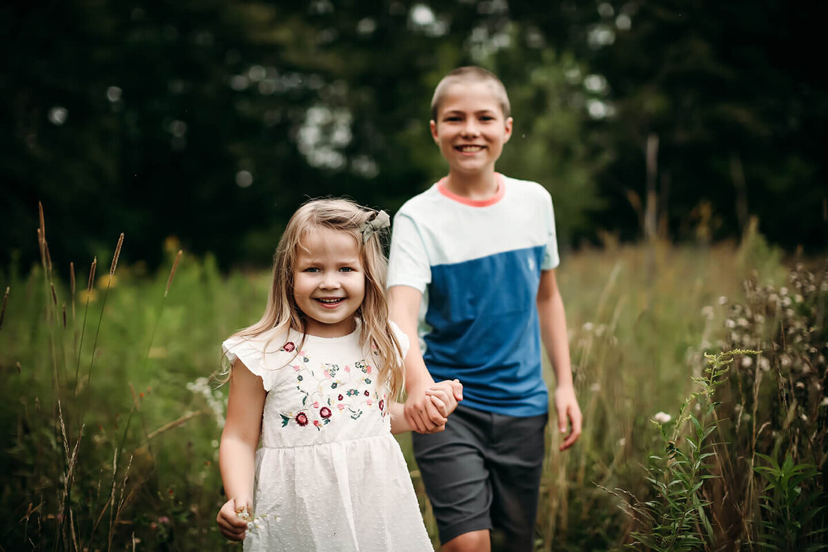 brother and sister holding hands through a field