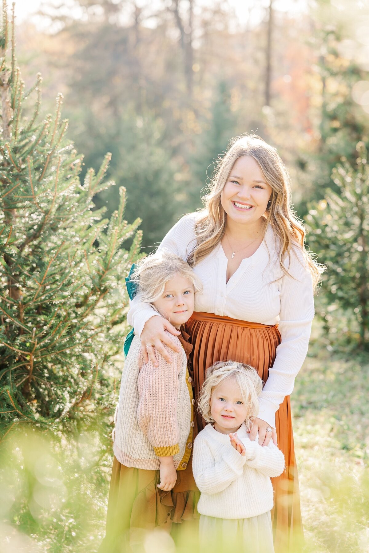 Mom and her two daughters at a Christmas tree farm