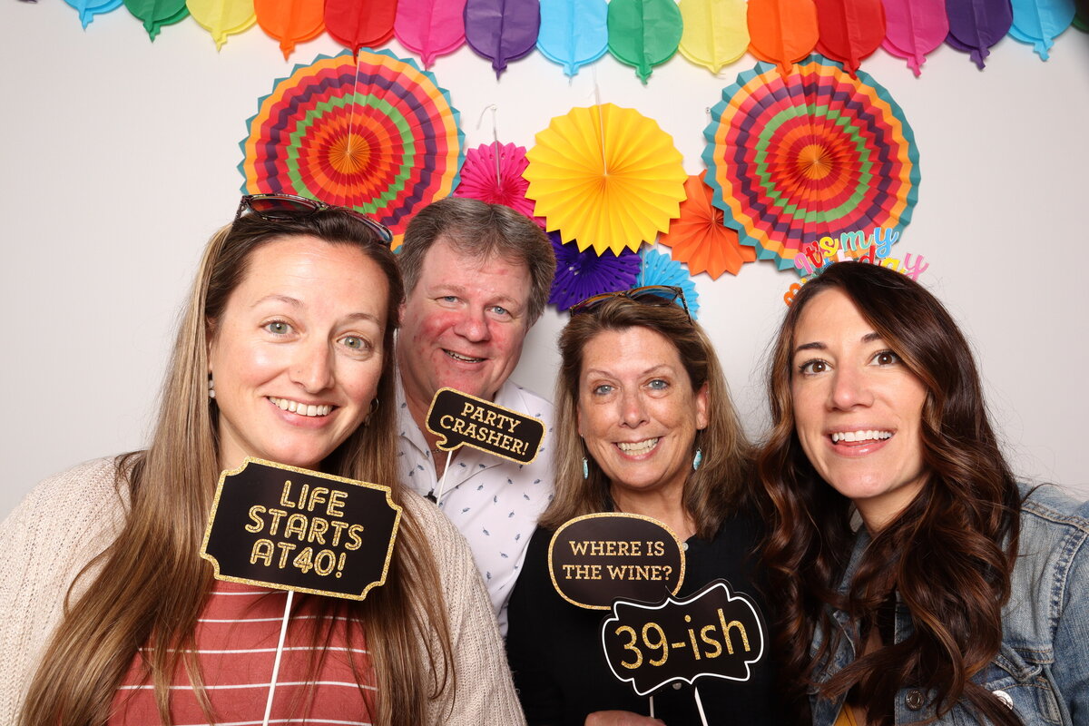 4 friends pose with funny props saying 39-ish and where is the wine?