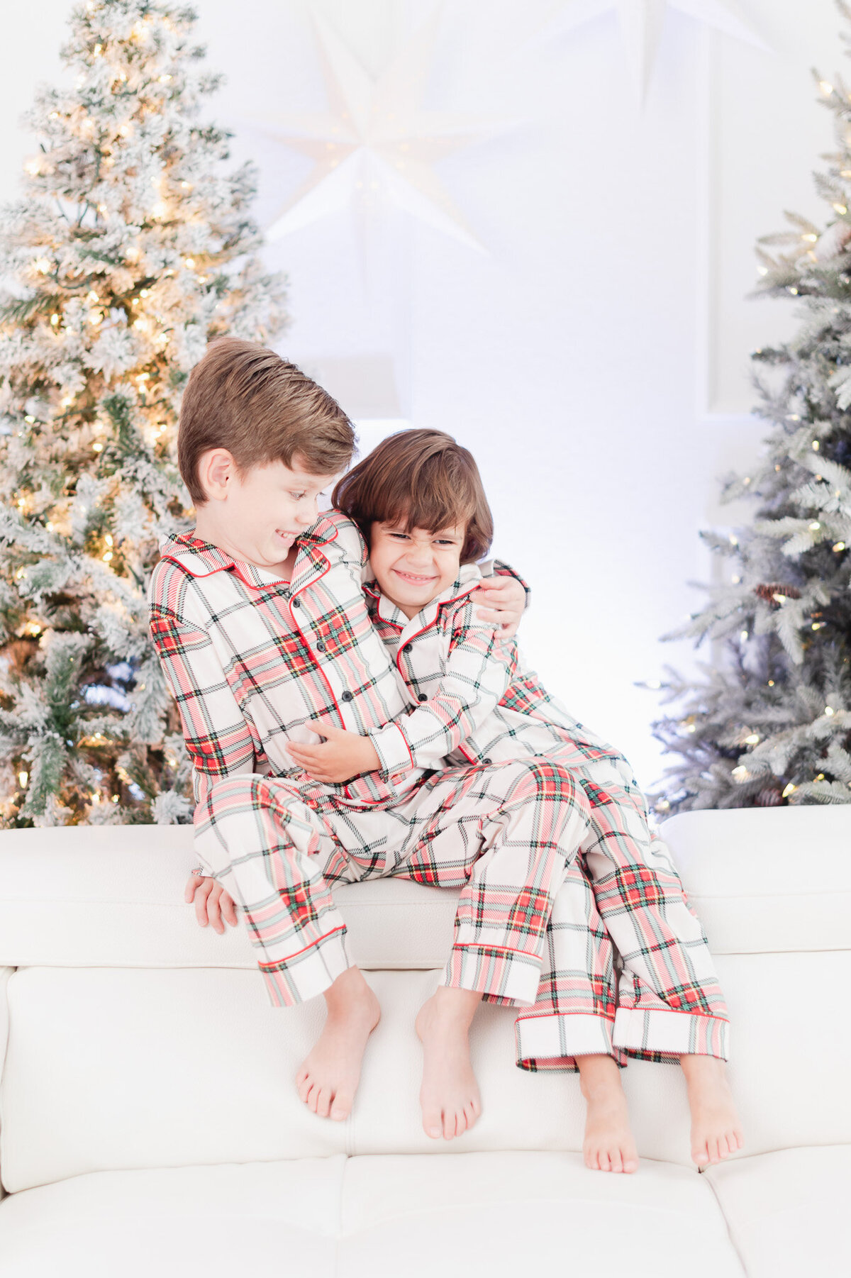 brothers hugging in front of the christmas tree