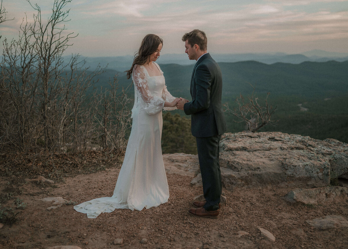 photo of bride and groom holding hands and praying during elopement on Mogollon Rim in Payson, Arizona