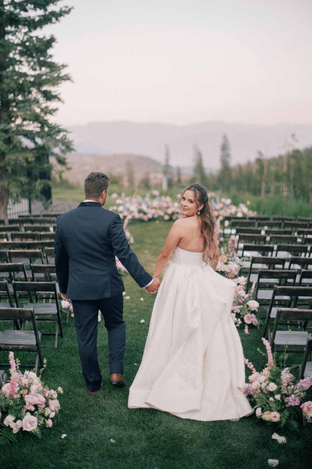 Bride and groom walking hand in hand down the aisle after their ceremony at a pastel summer wedding at Moonlight Basin.