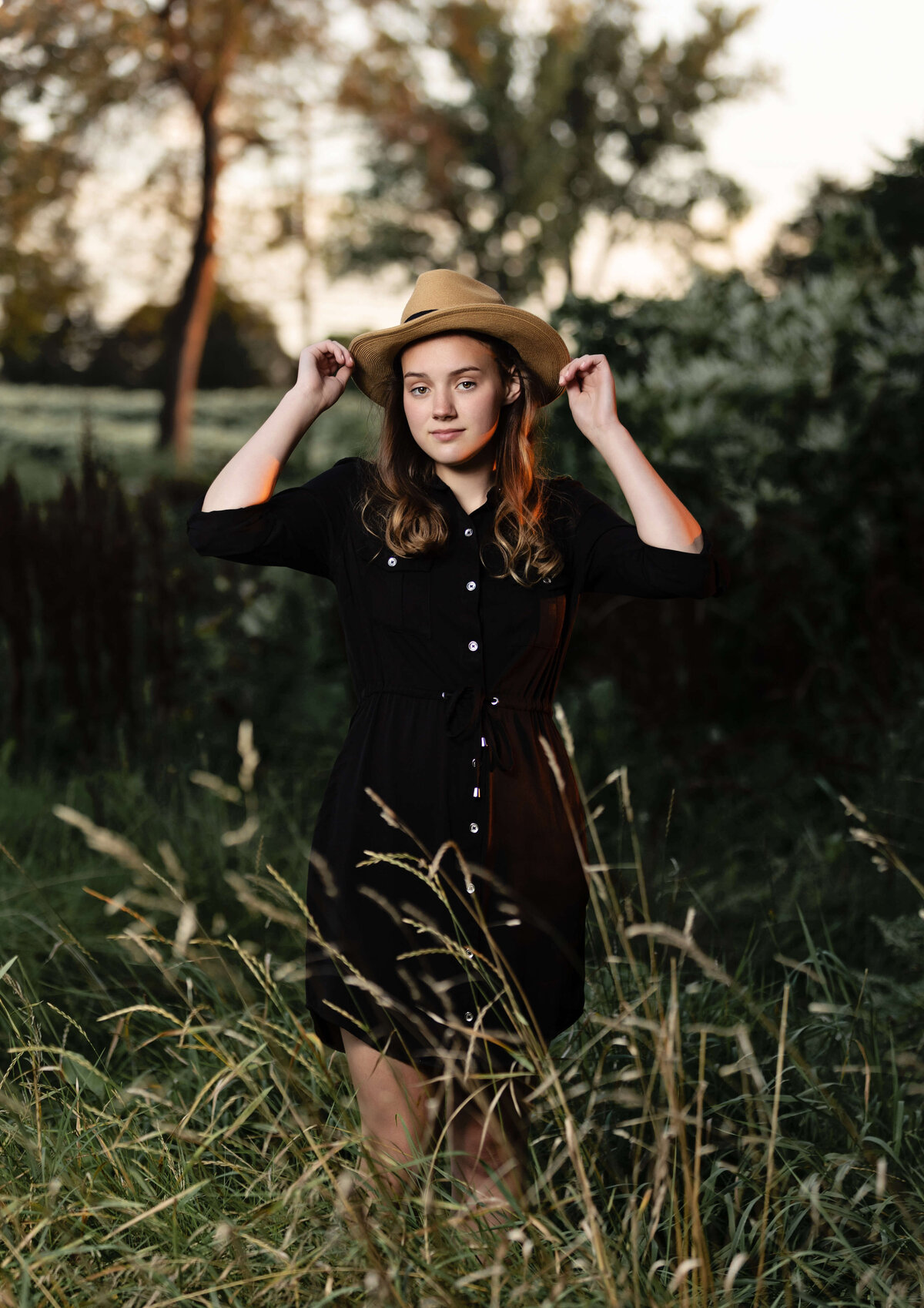 Senior photo of a girl with a hat on in an Erie Pa field