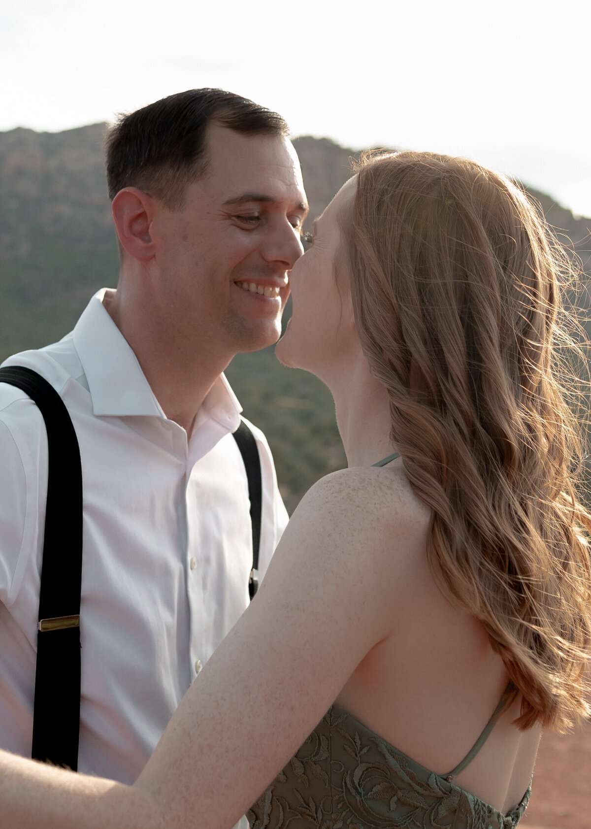 Couple standing against red rock backdrop during Sedona engagement session