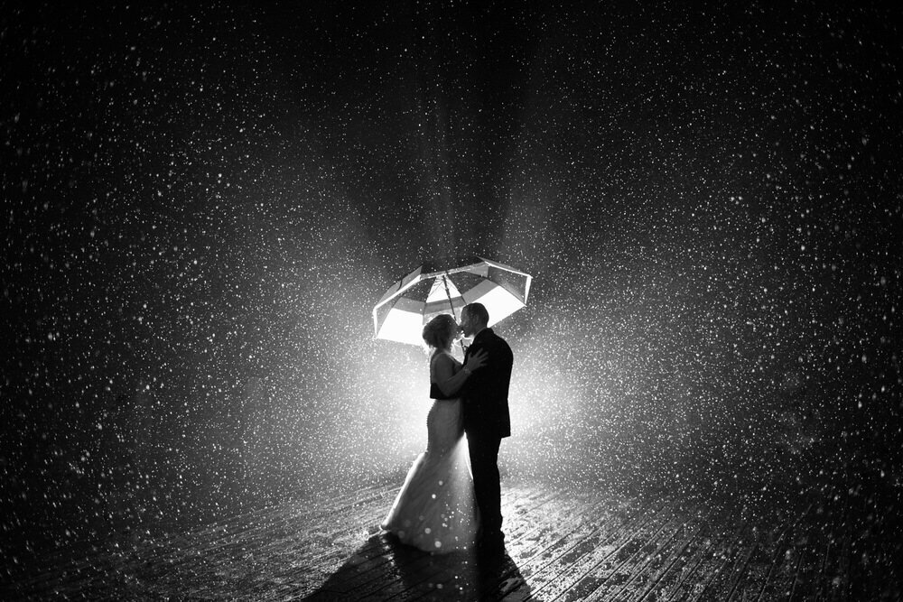 couple kisses in the rain under an umbrella 