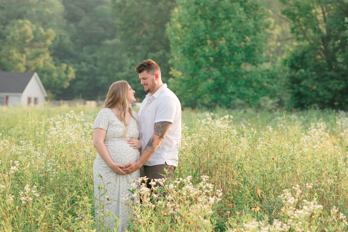 Portrait of an expecting couple embracing mom's baby bump in a field of wildflowers taken by missy marshall