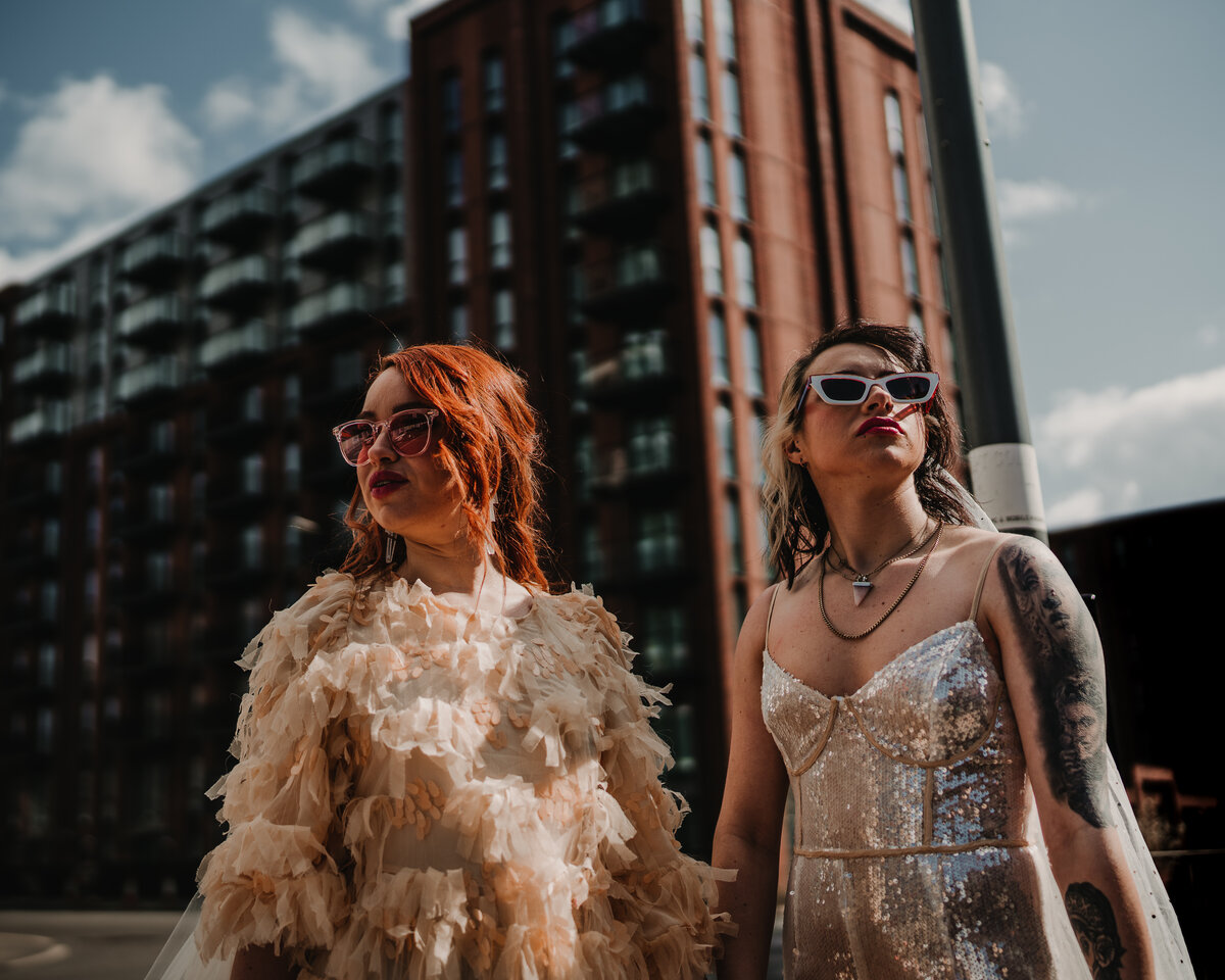 Cool wedding photography of two brides holding hands in the city