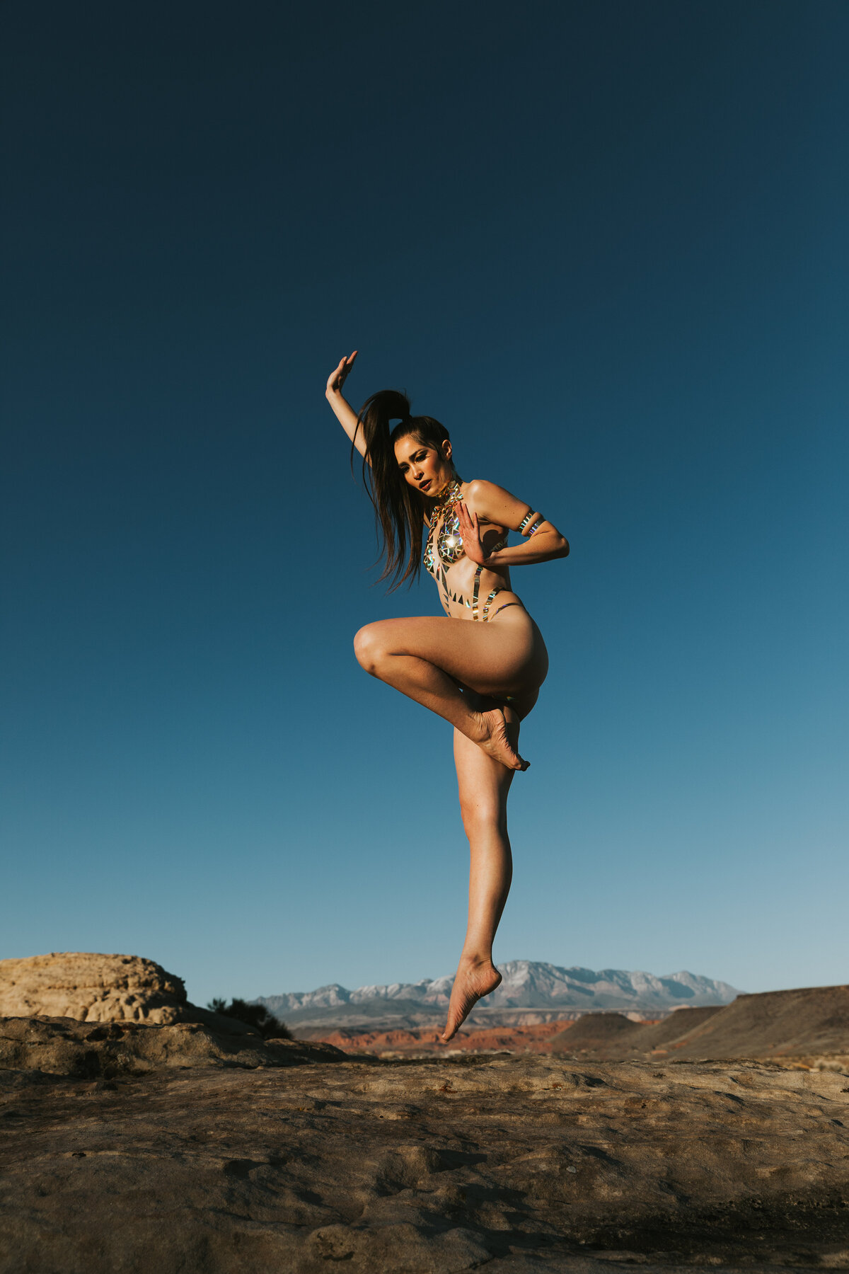 A woman is jumping high in the air while only wearing body tape to cover her.