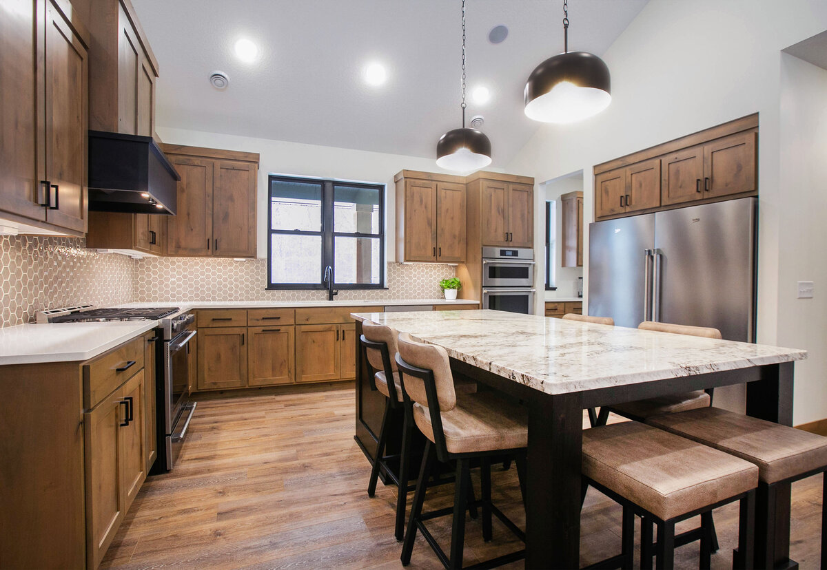 Open kitchen with dark cabinets, large island, and quartz countertops in an Elk River custom home