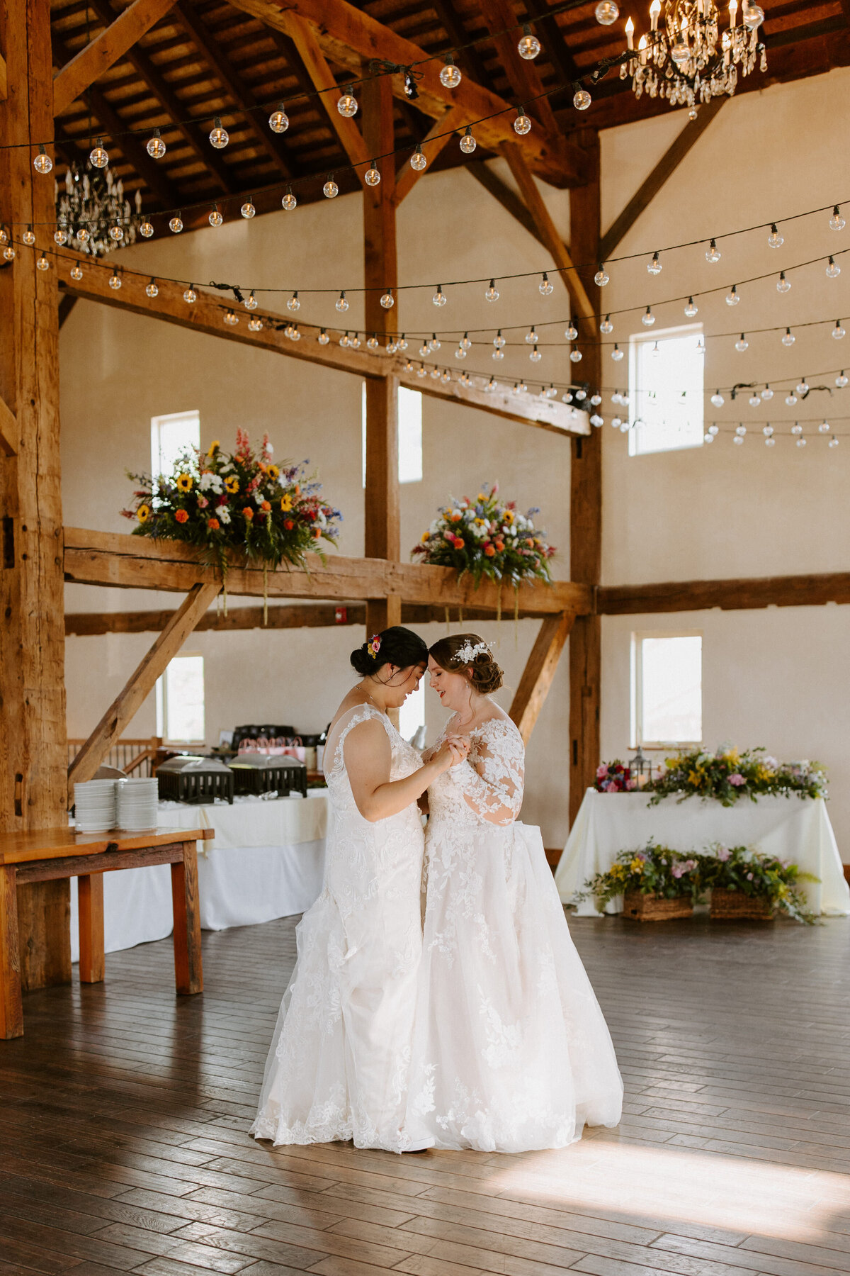 two brides dancing at in a rustic barn