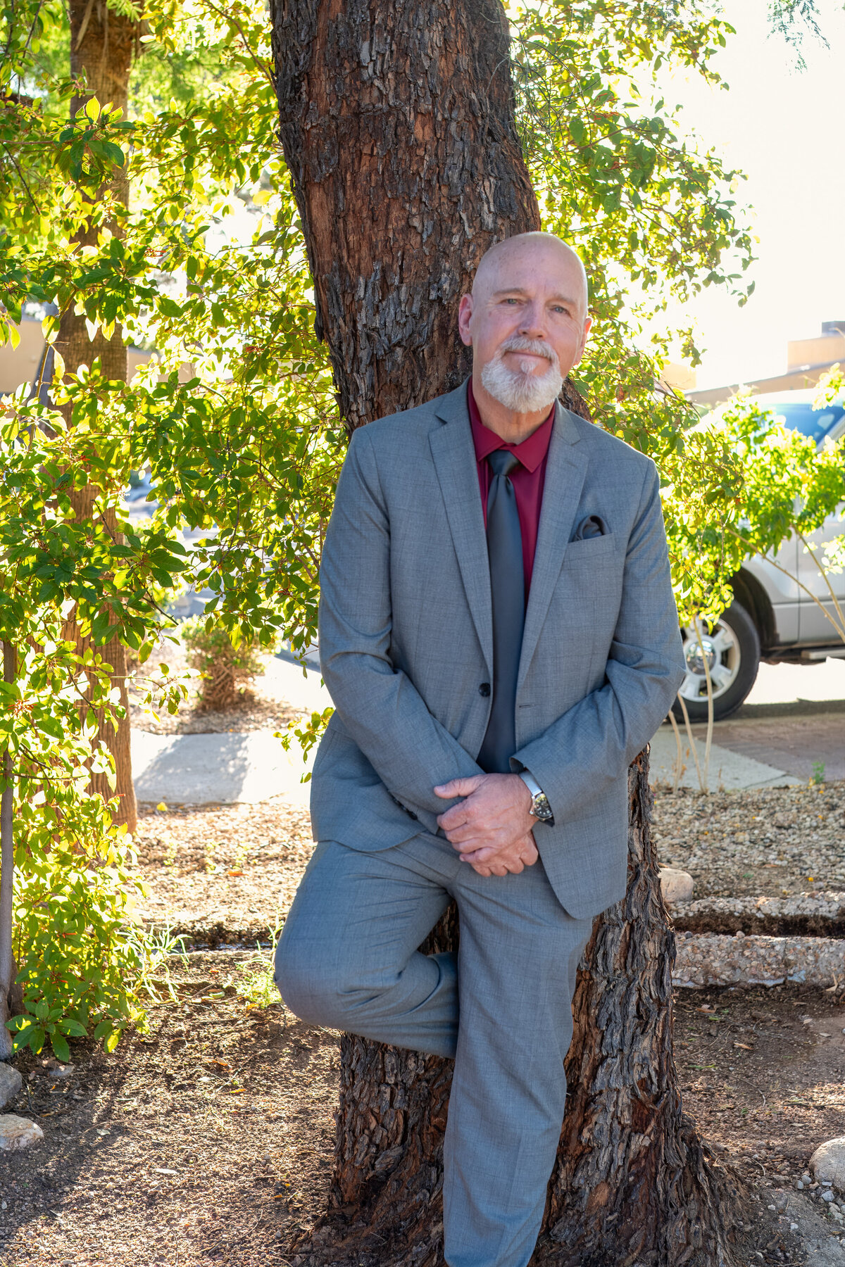 Man in a suit posing confidently beside a tree in an outdoor setting, photographed by Vyrl Photo, highlighting Tucson brand photography.