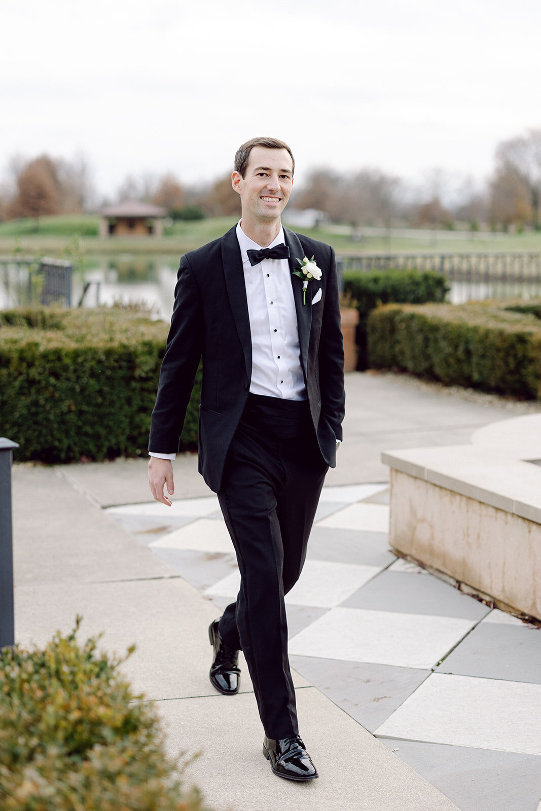 Groom walking beside a fountain at a beautiful Columbus wedding venue shot by a philly wedding photographer