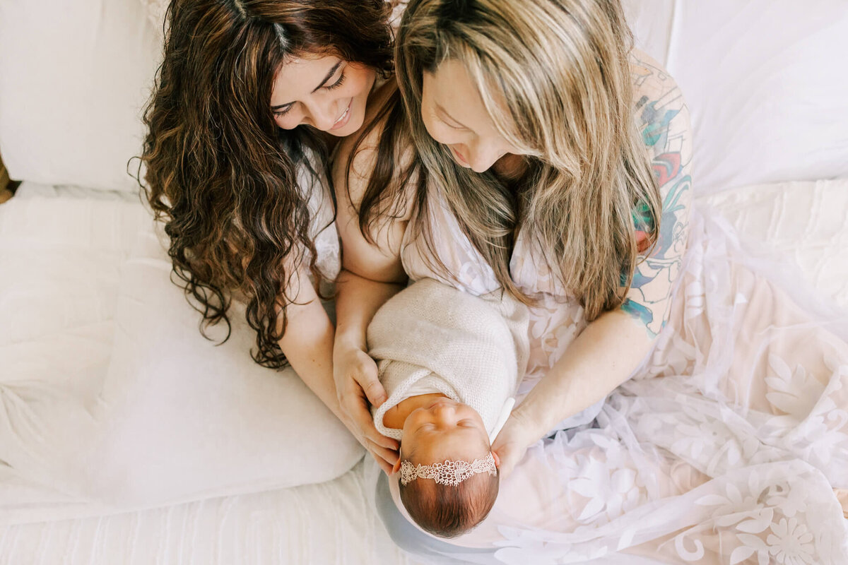 portrait of two moms holding their newborn baby girl.