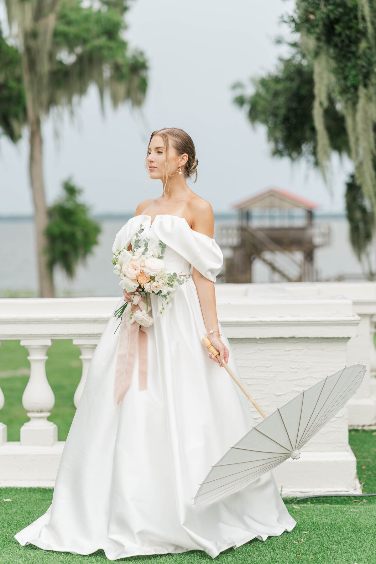 bride looking to the side while holding a peper umbrella, she is standing