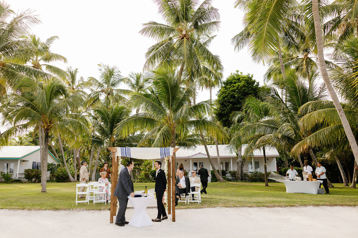 A serene beachfront wedding setup featuring a chuppah under the palm trees at Casitas at Cheeca. Florida Keys micro wedding by Claudia Amalia Wedding Photography.