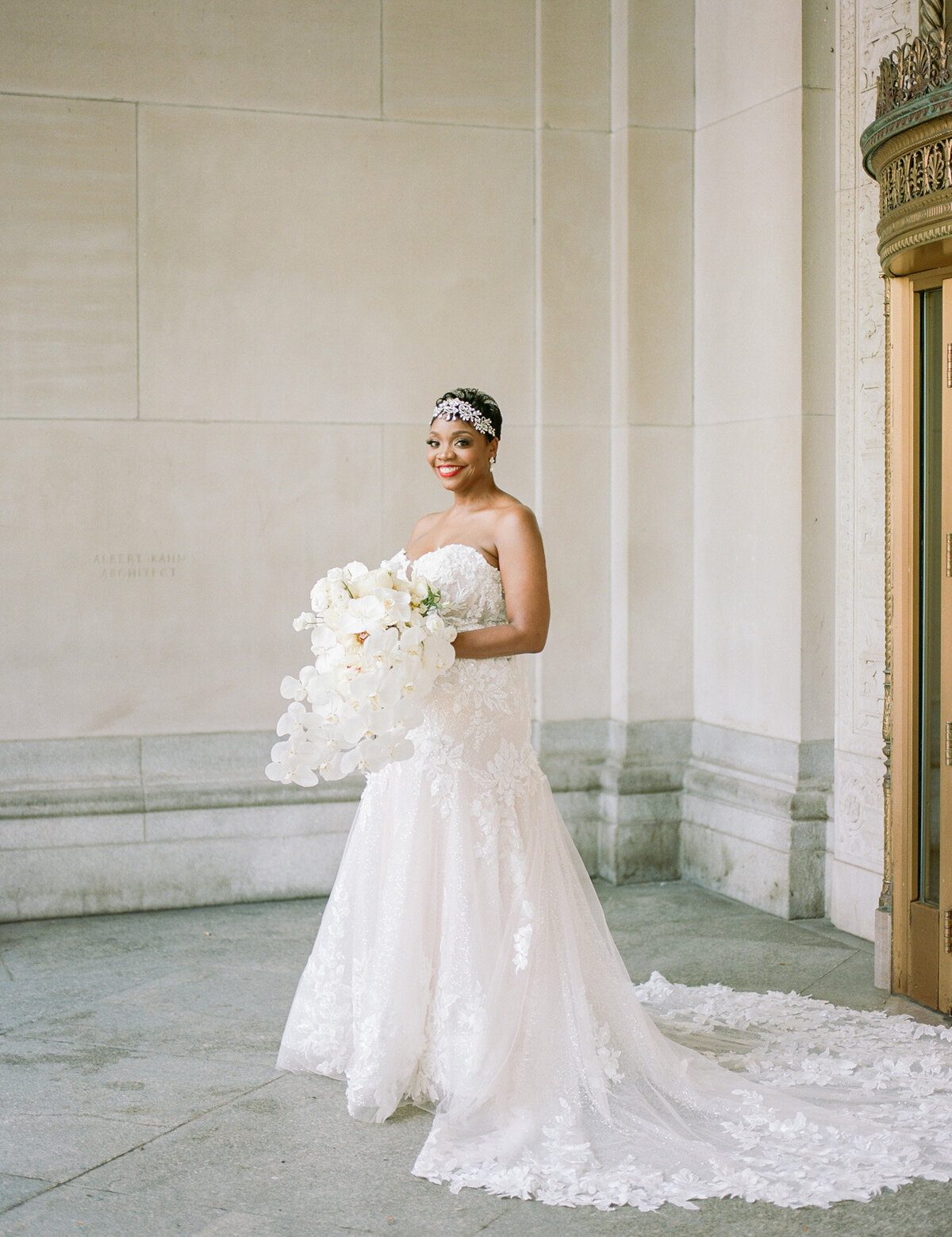 beautiful black bride with white orchid bouquet and lace gown with Detroit architecture, captured by Michigan film wedding photographer Christina Harrison