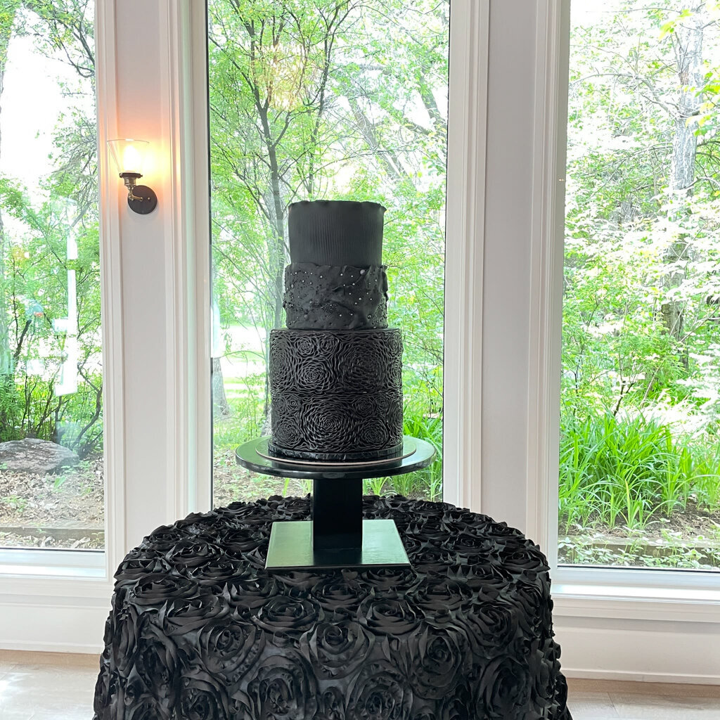 Bold black coloured three-tiered textured wedding cake with black floral details, created by Chartier YYC, elegant cakes & desserts in Calgary, AB, featured on the Brontë Bride Vendor Guide.