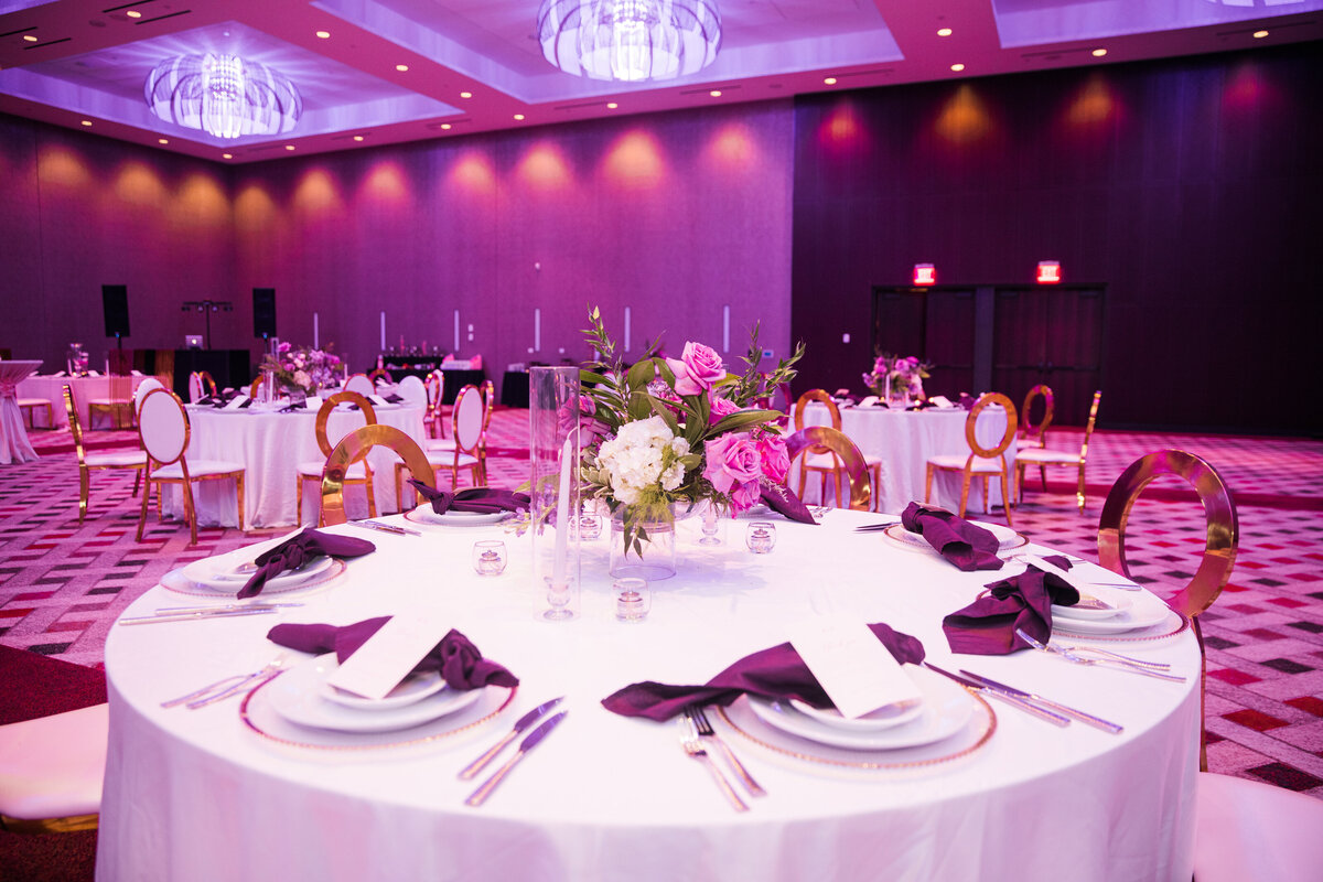 white plates with purple napkins on a white table in a room with purple lighting