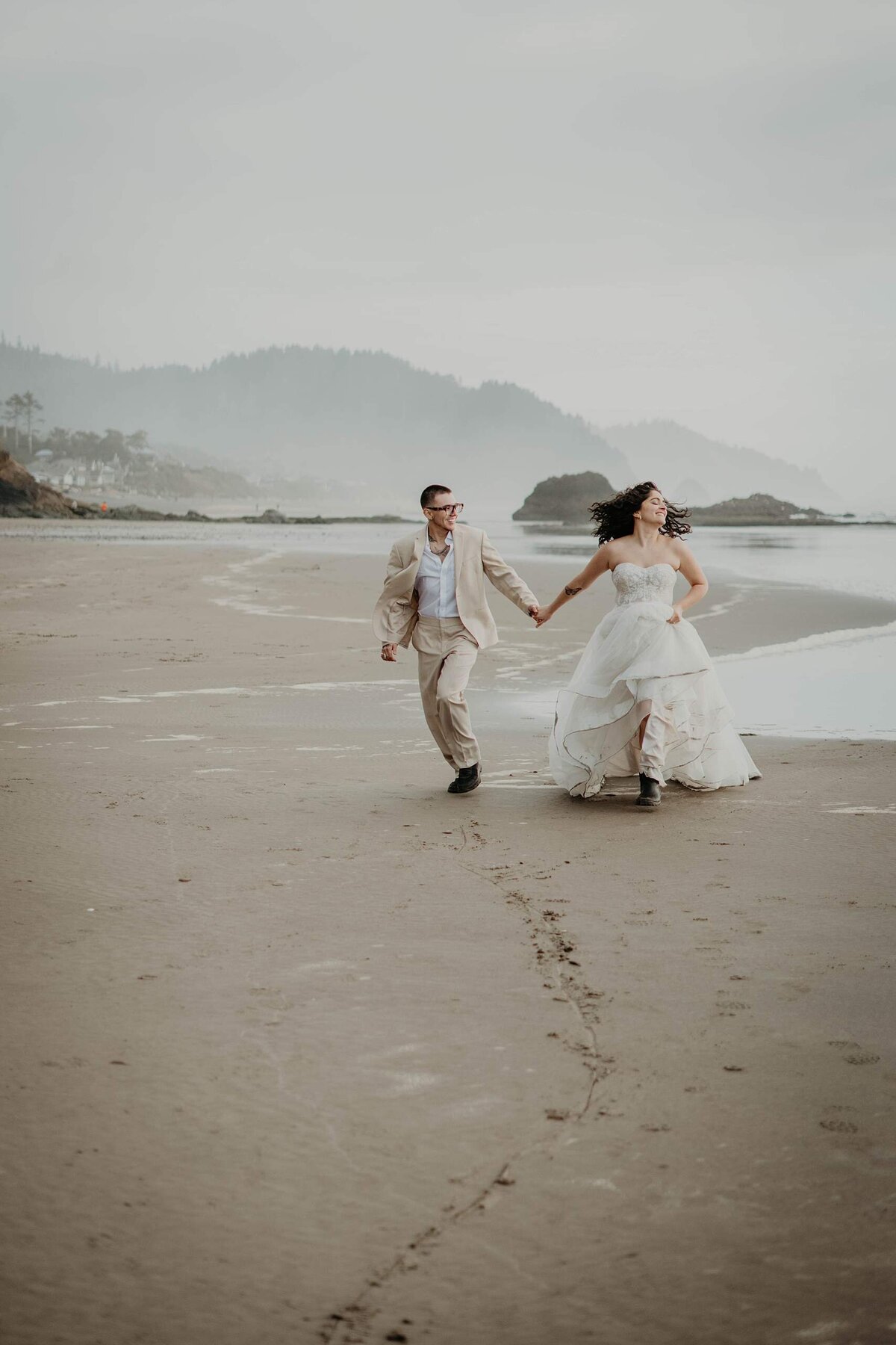Couple running down the beach during their Oregon Coast elopement
