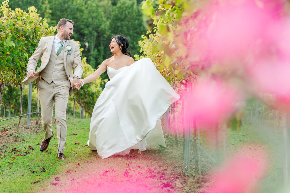 wedding couple run through vineyard and roses at Dugaren Vineyards