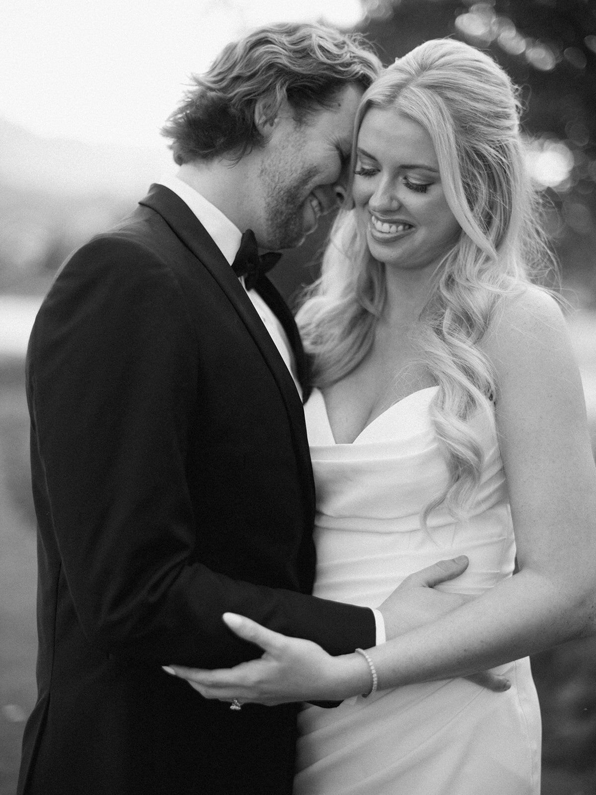 Romantic black and white photo of bride and groom embracing during golden hour at Waynesville Inn wedding.
