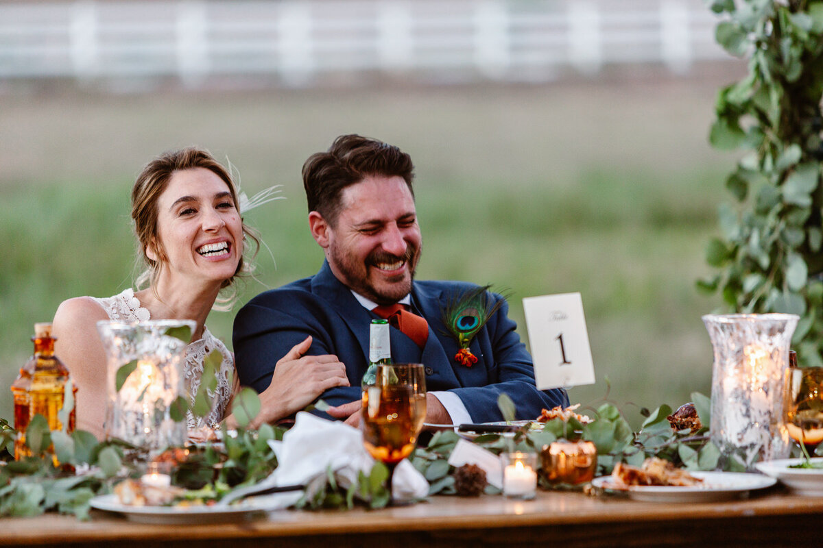 A couple laughs and cries at the table during their wedding day.