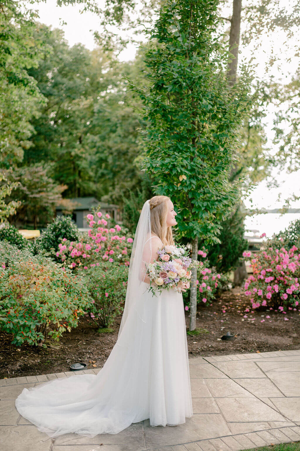 Bride looking out into the distance holding her pink flower boquet and surrounded by pink flowers at her DC wedding venue