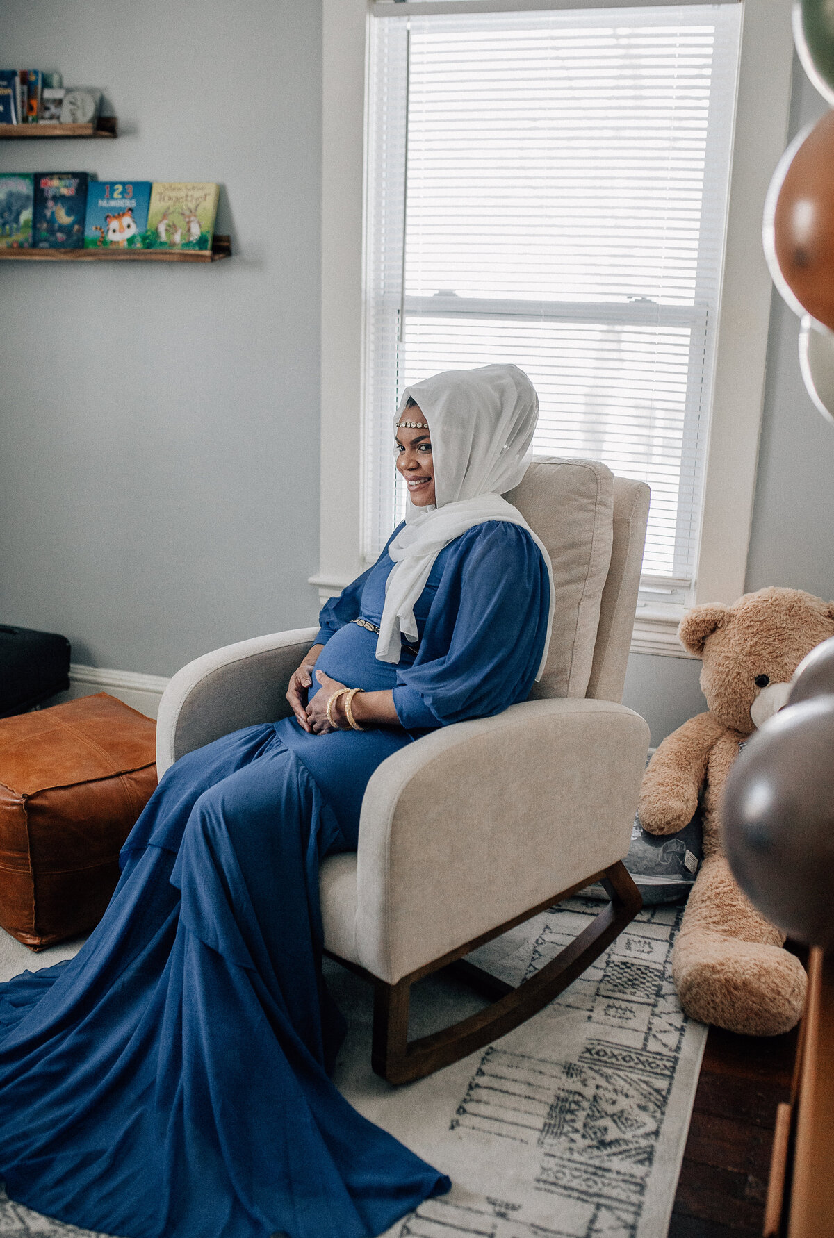 Maternity photoshoot of soon to be mom sitting in a chair in baby room.
