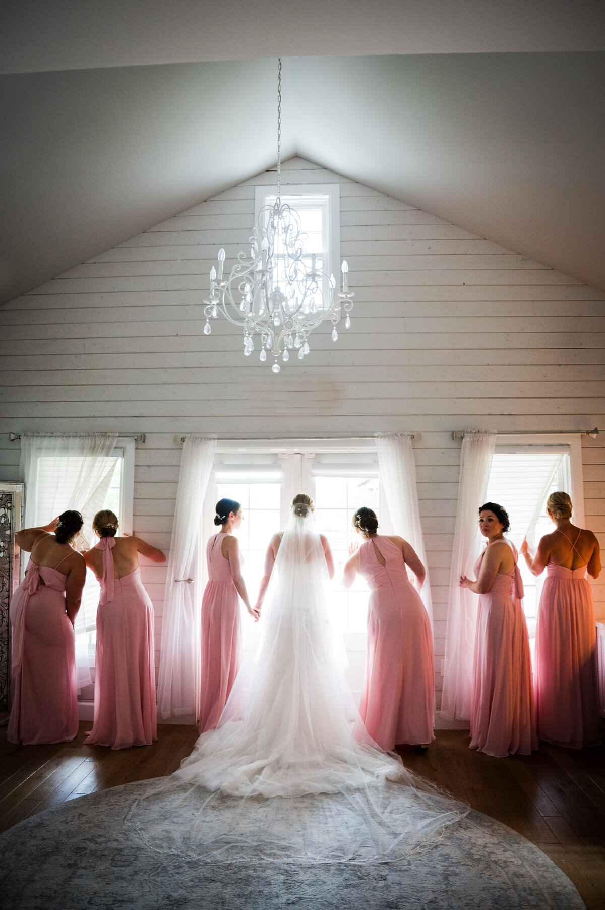 A bride and her bridesmaids stare out the windows at The Barn at Raccoon Creek in Denver, Colorado.
