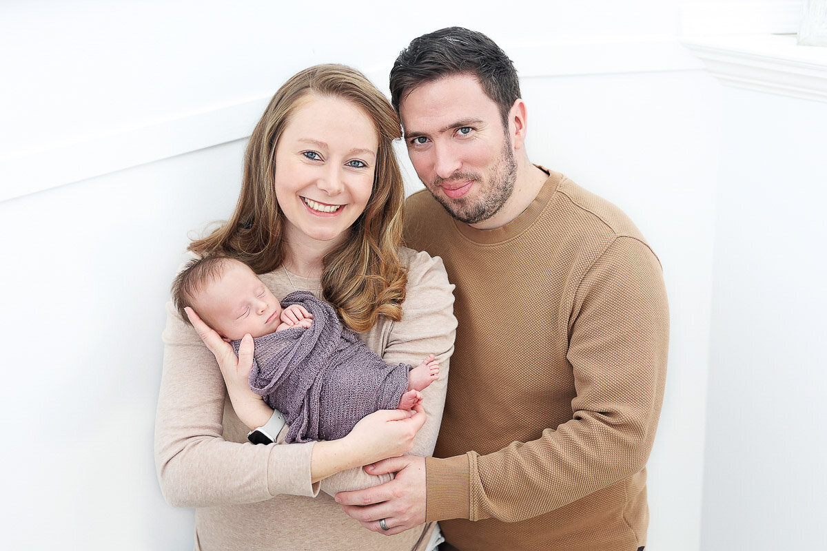 Parents holding newborn baby in their hands at home photo session in Calgary Alberta
