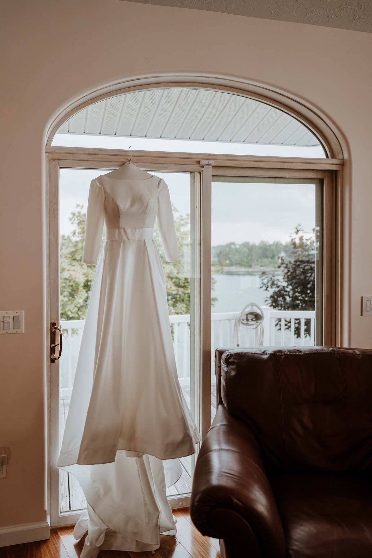 Wedding dress hanging in a glass sliding door.