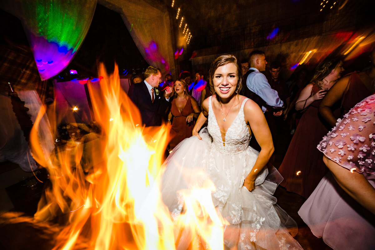 One of the top wedding photos of 2020. Taken by Adore Wedding Photography- Toledo, Ohio Wedding Photographers. This photo is of a bride dancing while being surrounded by people and fire
