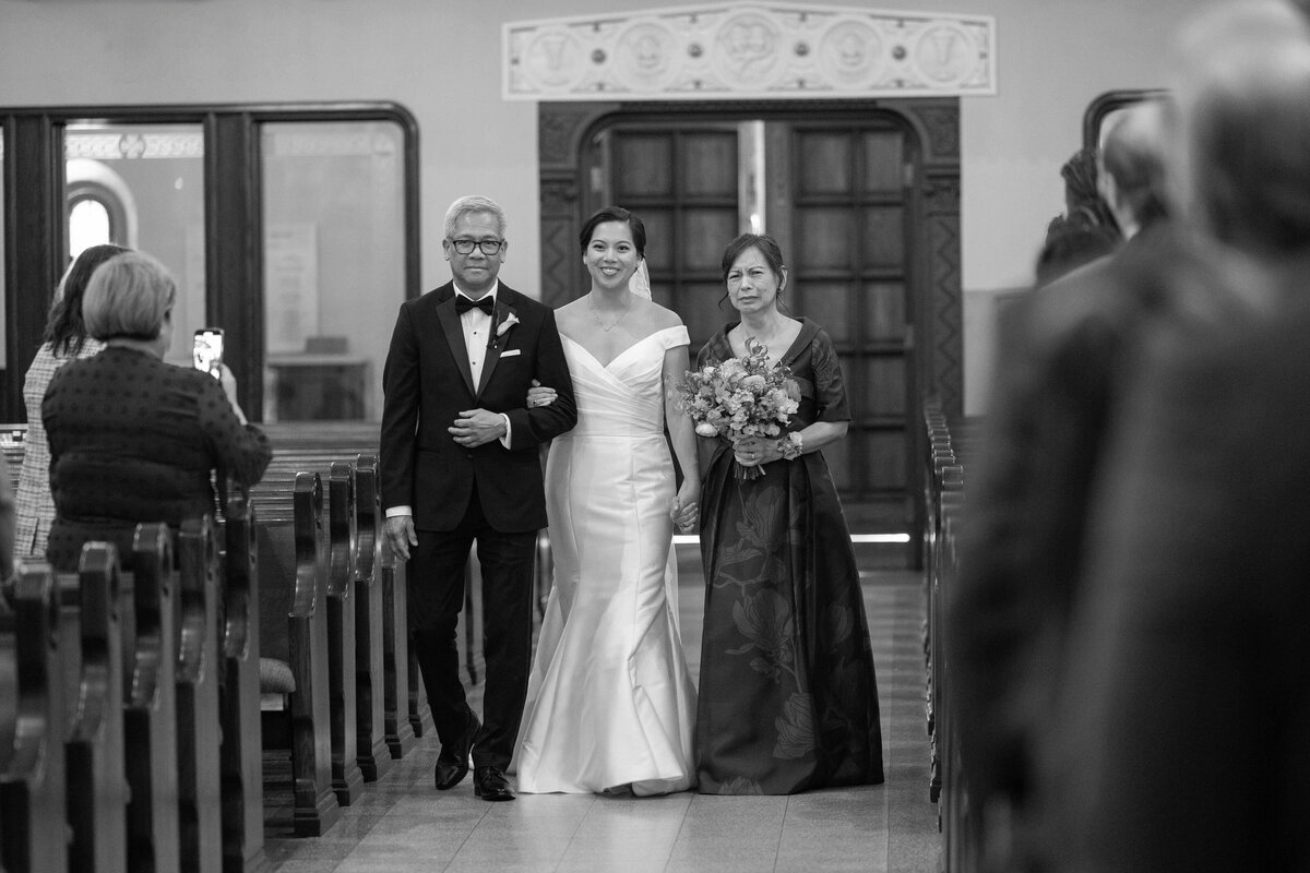 Bride walking with parents at St Monica's