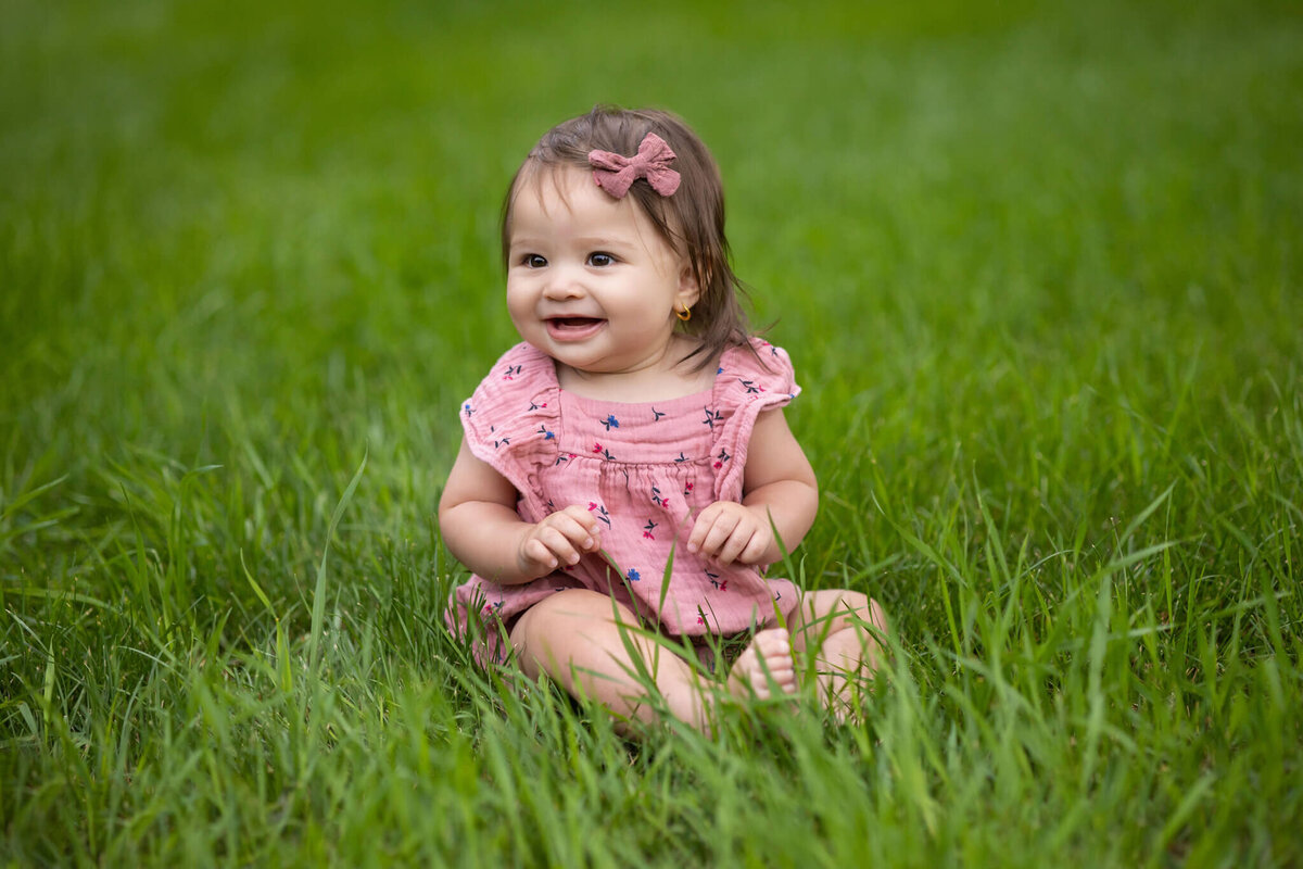 young child sitting in the grass smiling