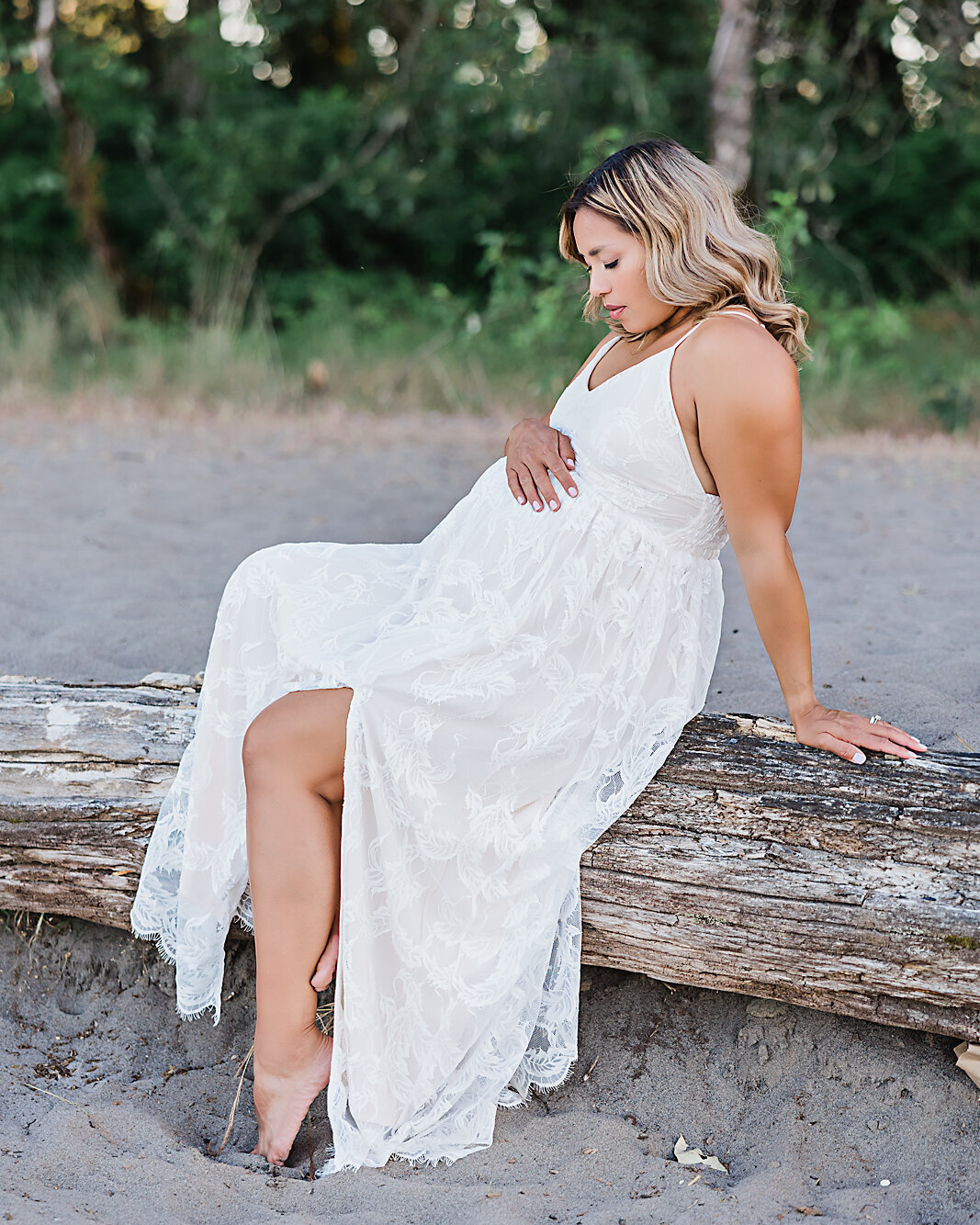 white dress mom sitting on log in maternity session with ann marshall photography