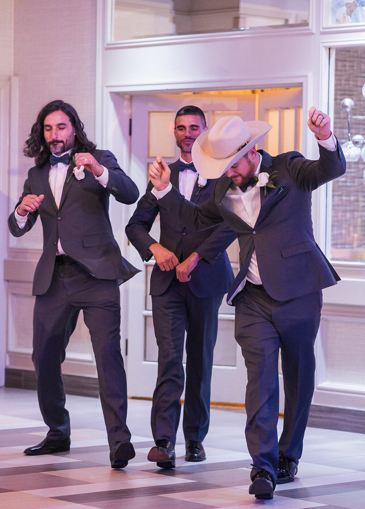Trio of groomsmen walking into reception.