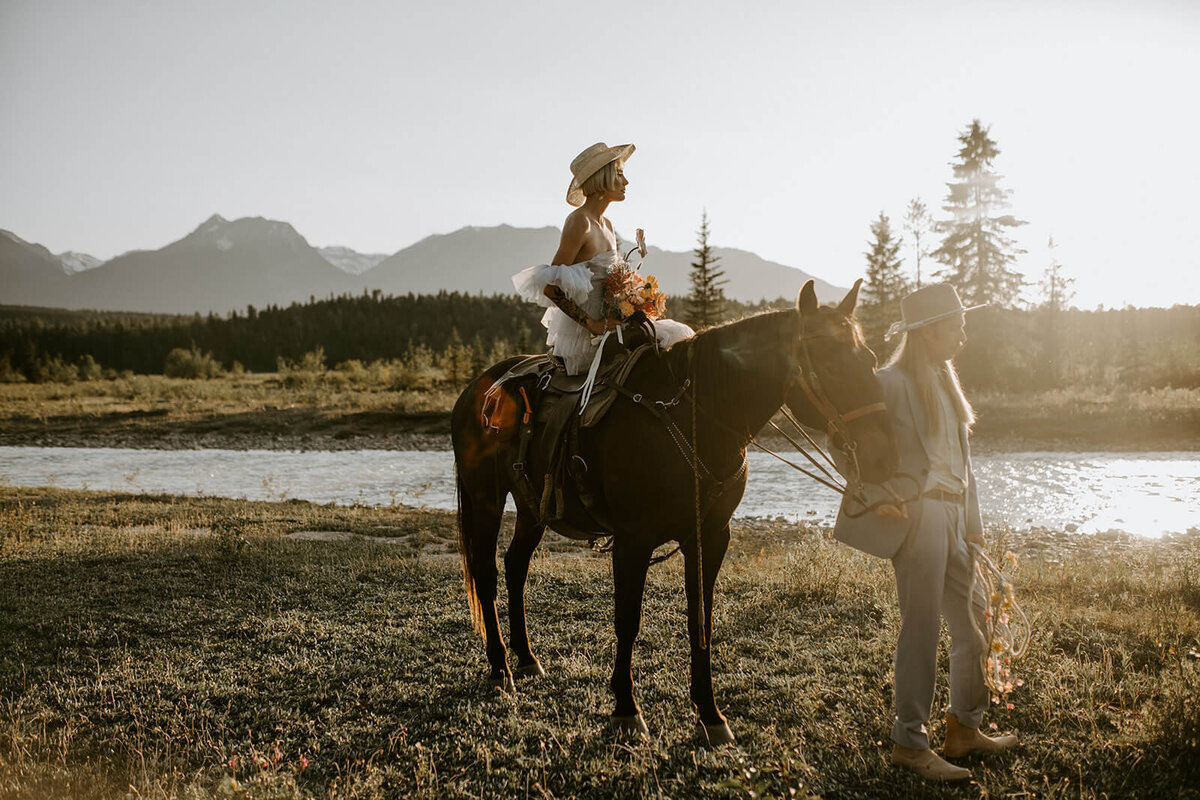 Woman-on-horse-at-elopement-in-front-of-mountains-with-groom