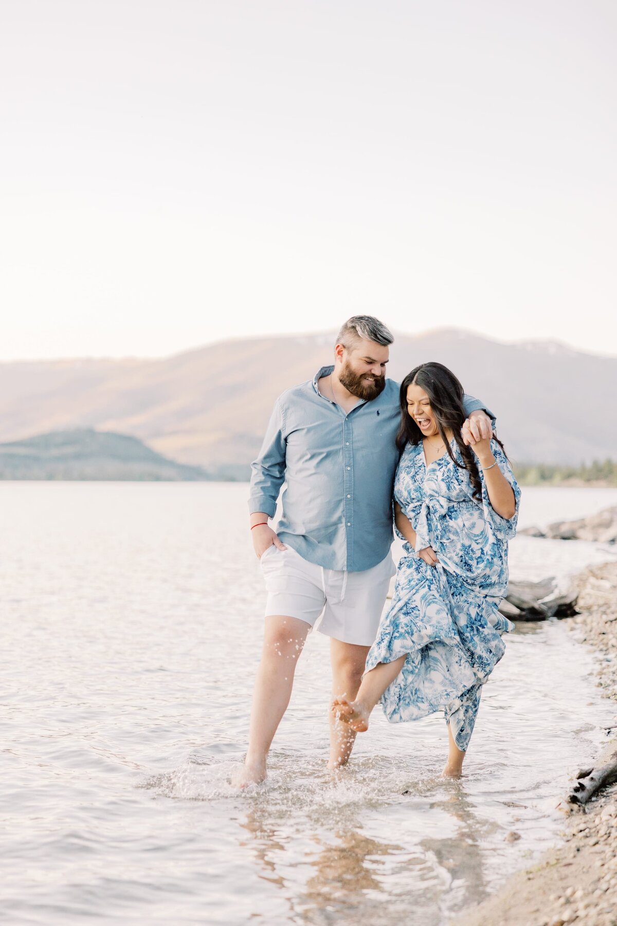 A young couple are walking hand in hand while splashing their toes in Lake Dillon. Taken by a local Breckenridge Photographer.