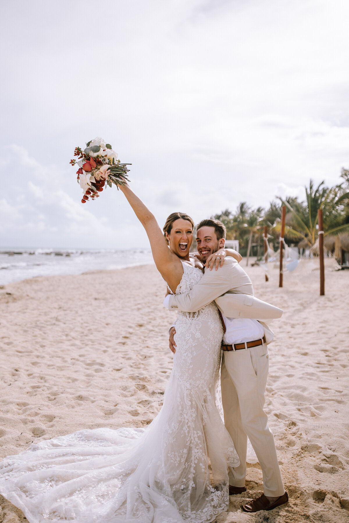 Bride and groom cheering on the beach at their destination wedding in Mexico. 